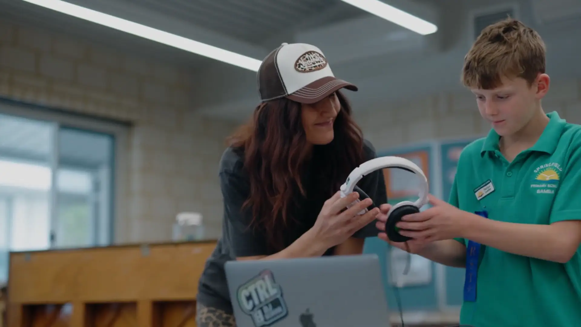 Miss Tash handing headphones to a young DJ student